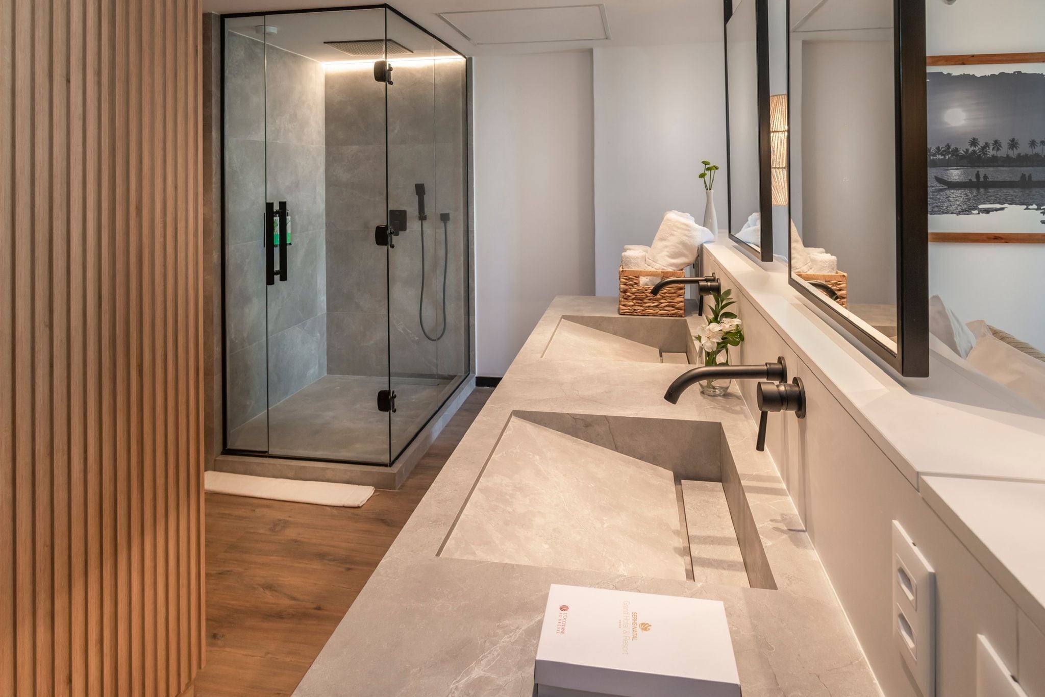 Un baño moderno con ducha envuelta en vidrio, un lavamanos grande y un espejo sobre el mostrador.