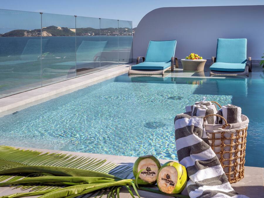 A poolside area with two lounge chairs, a wicker basket with towels, and coconuts.