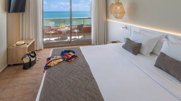 Ein Hotelzimmer mit einem großen Bett, einem Fernseher, einem Balkon mit Meerblick und einem Tisch mit Frühstücksangeboten.