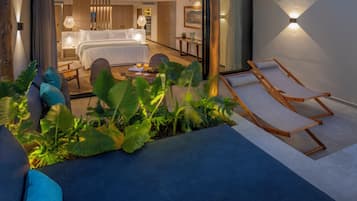 Et moderne hotelværelse med en stor seng, et opholdsområde med sofabord og en balkon med liggestol.