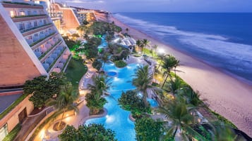 Ein Resort mit Swimmingpool, Palmen und Blick auf den Strand.