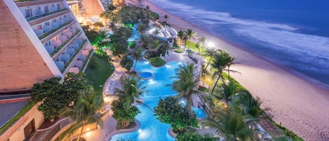 Un resort con piscina, palmeras y vista al mar.