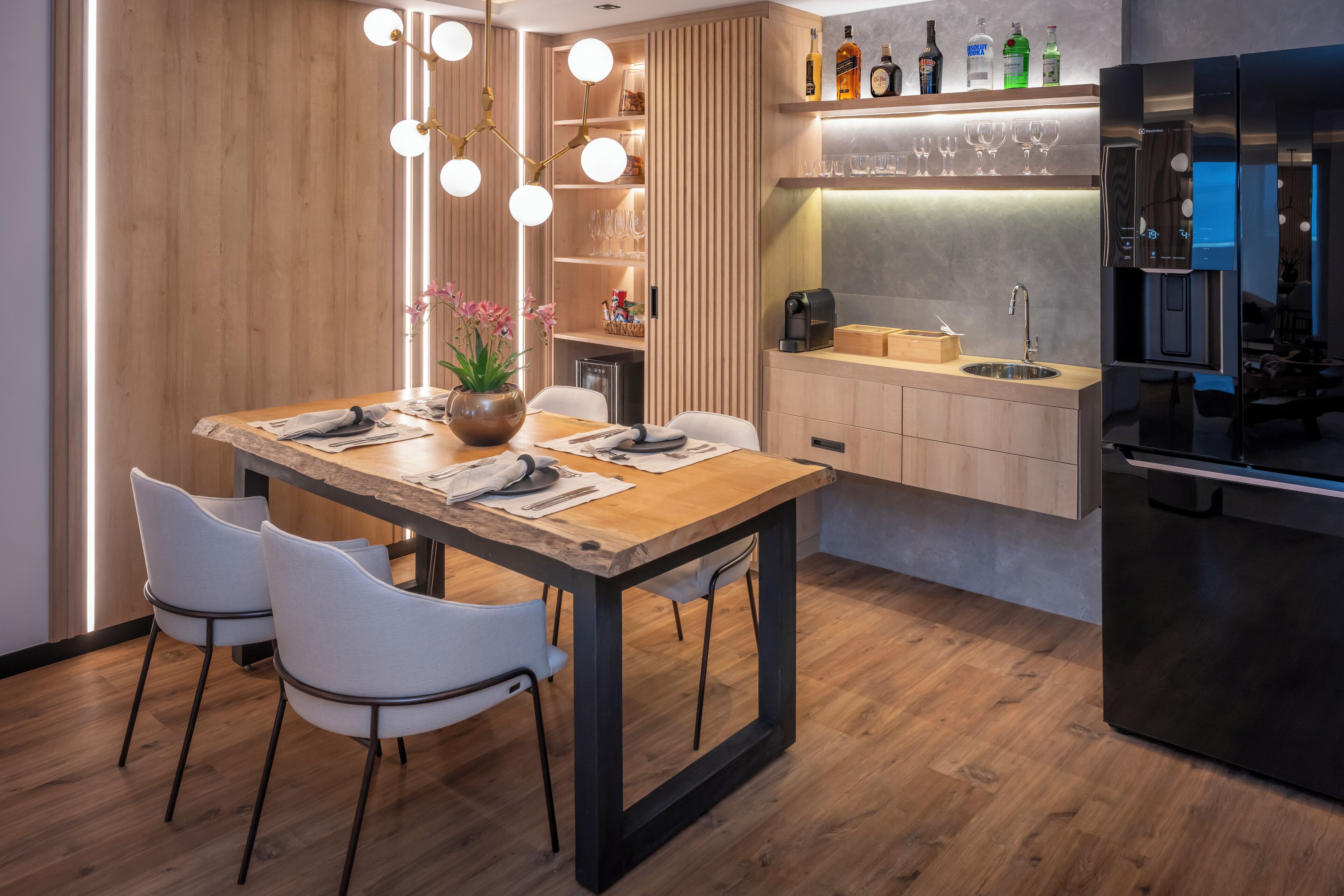 A modern kitchen with a wooden dining table, chairs, and a built-in coffee machine.