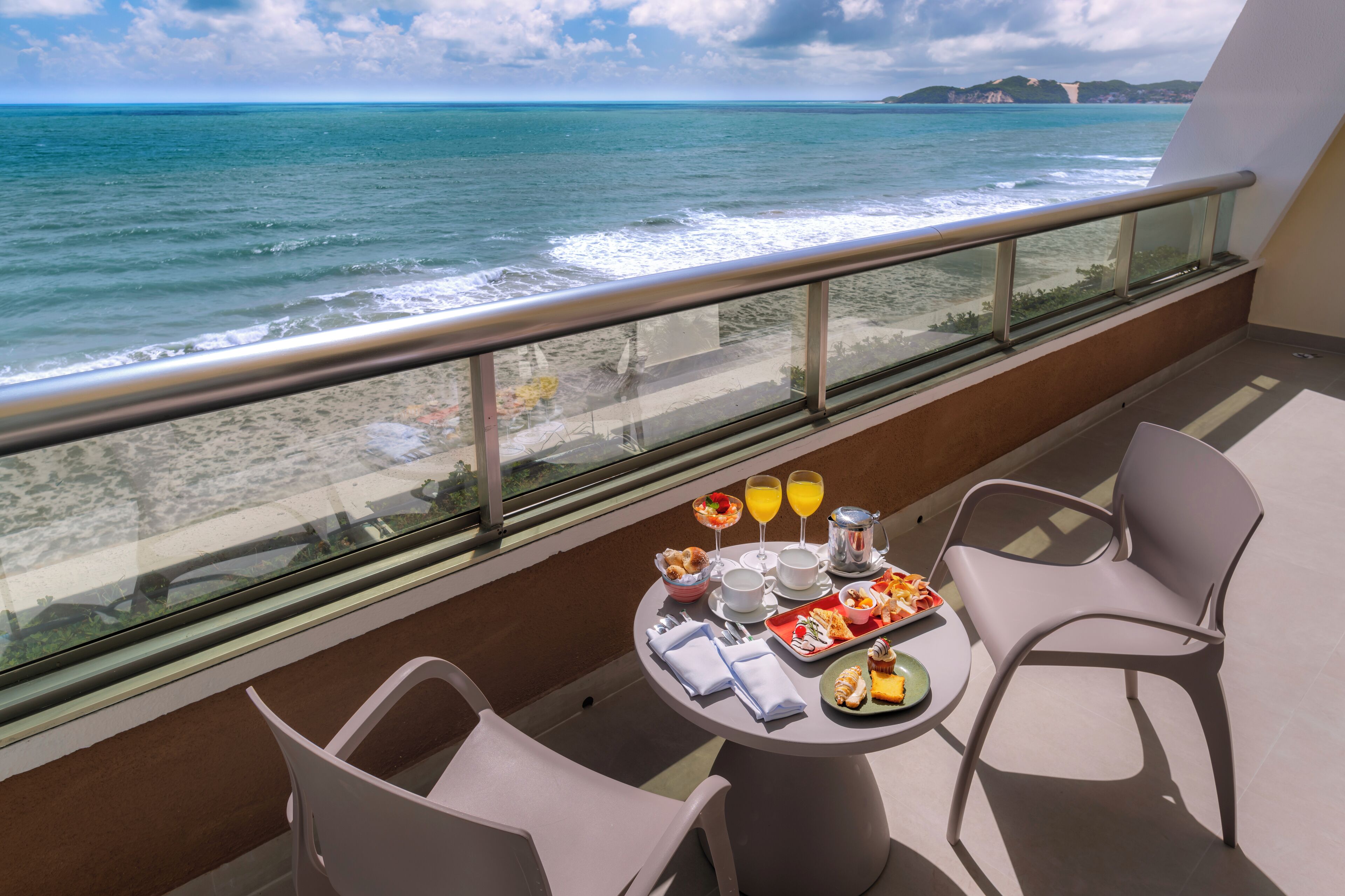 Un balcón con una mesa lista para el desayuno, con vista al océano.