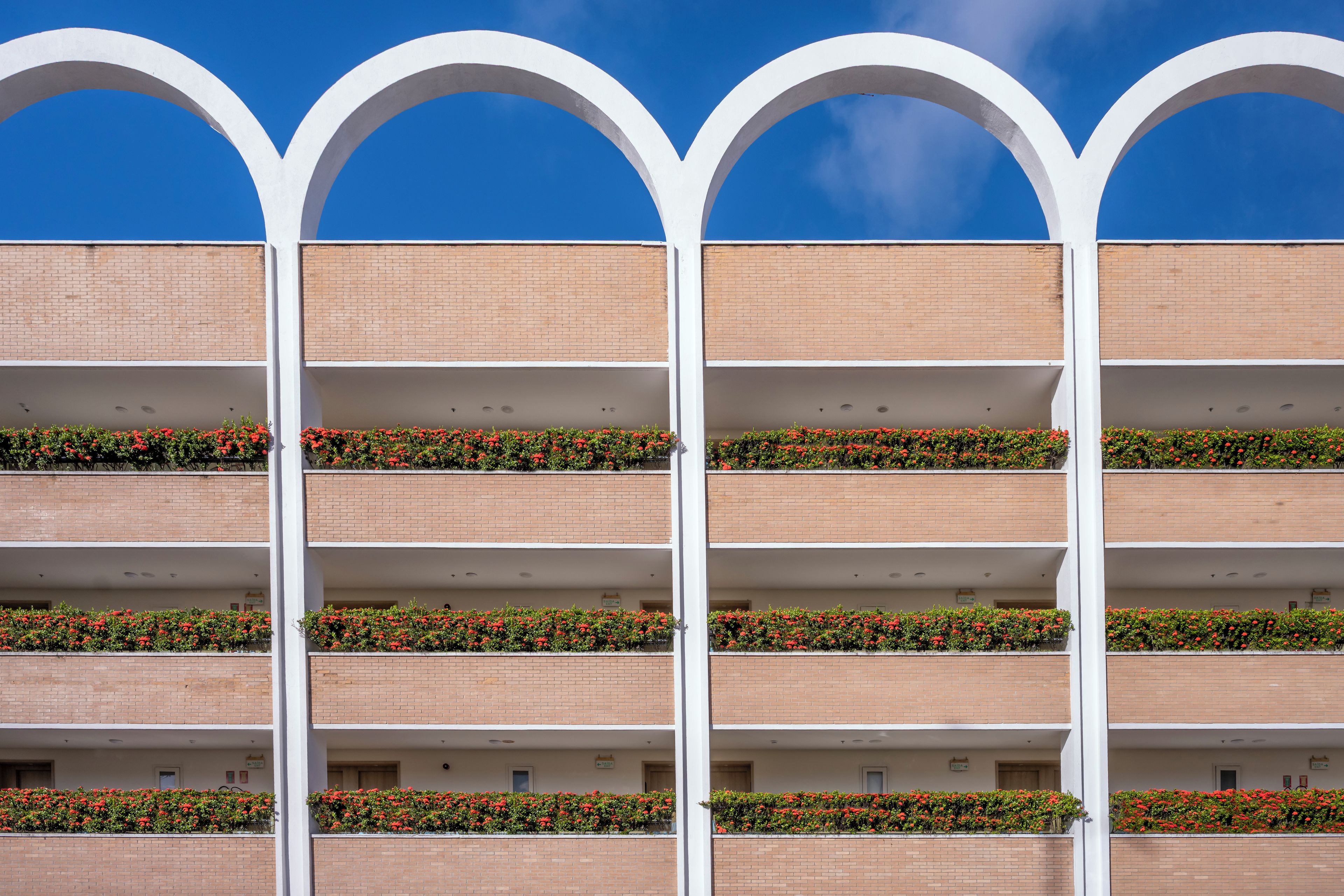 Un edificio de varios pisos con fachada de ladrillo y arcos blancos en la parte superior.