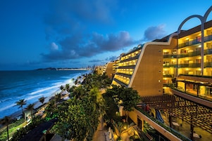 Un hotel con varios balcones con vistas al océano, un área de piscina y vista a la playa.