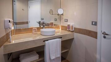 Un baño moderno con un espejo grande, un espejo redondo, un lavabo y un perchero para toallas.