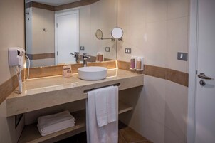 Un baño moderno con un espejo grande, un espejo redondo, un lavabo y un perchero para toallas.