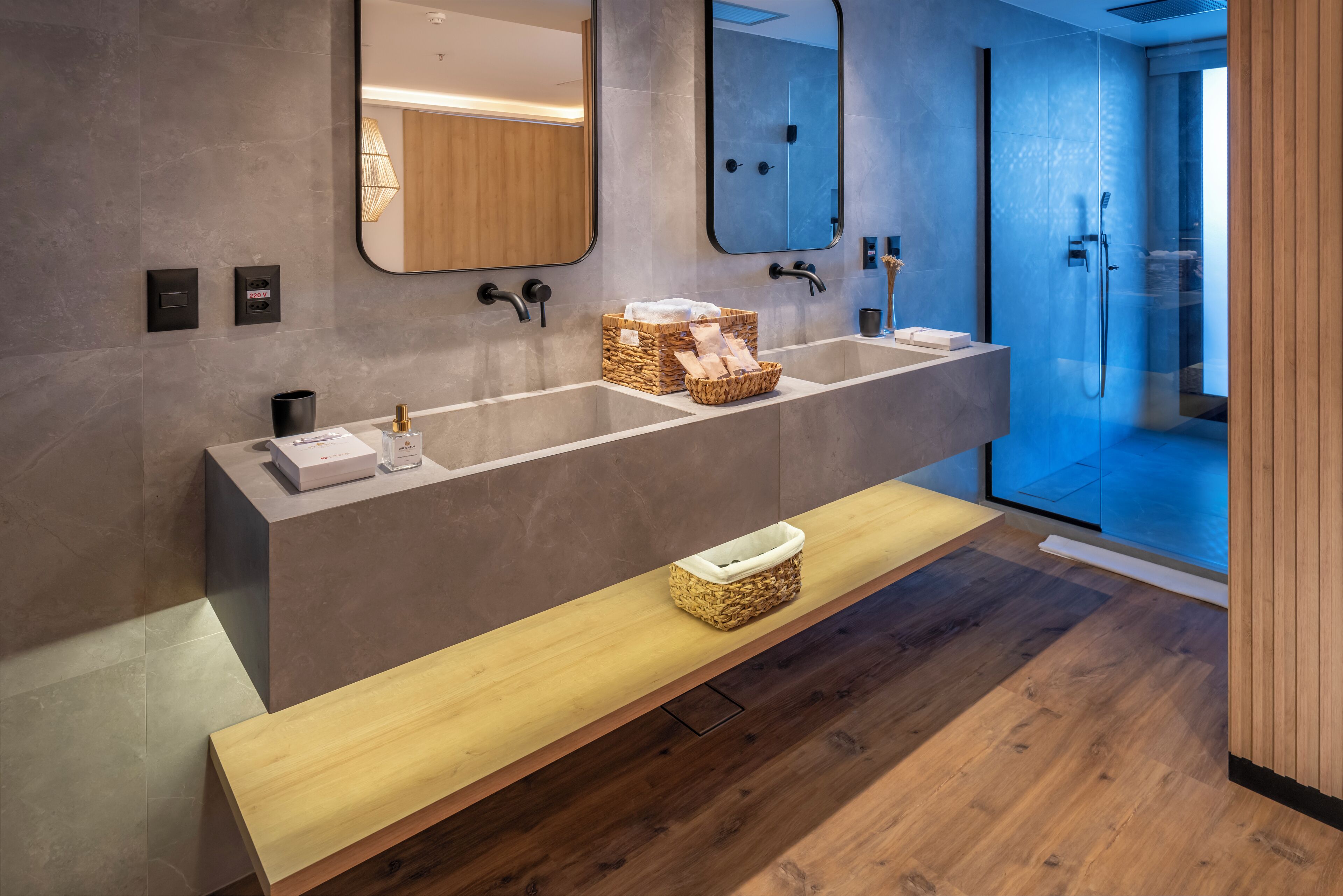 A modern bathroom with a large vanity, two sinks, and a bench.