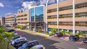 Um hotel com vários andares, design moderno e um estacionamento com diversos carros.