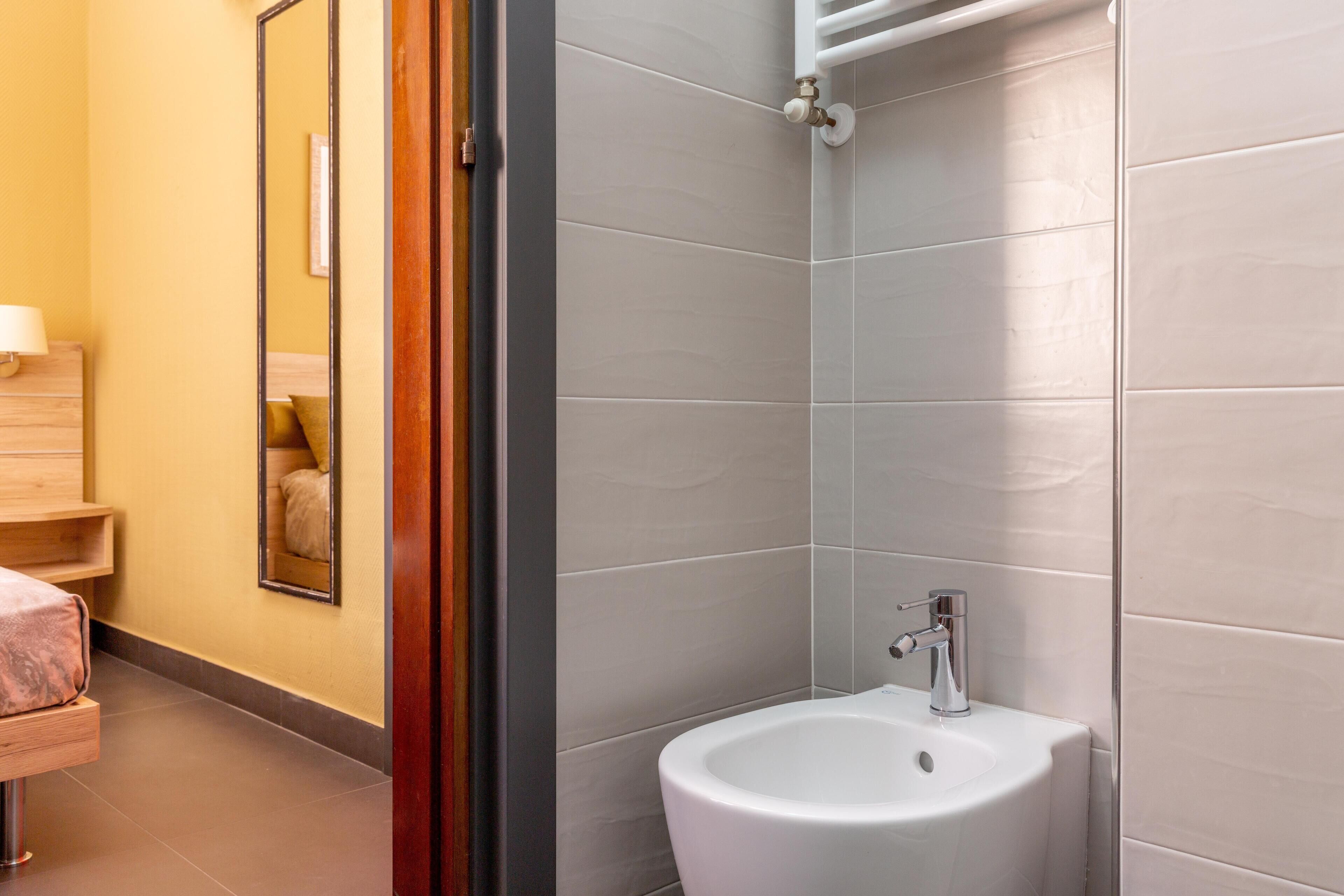 A bathroom with a white sink, a mirror, and a wooden vanity.