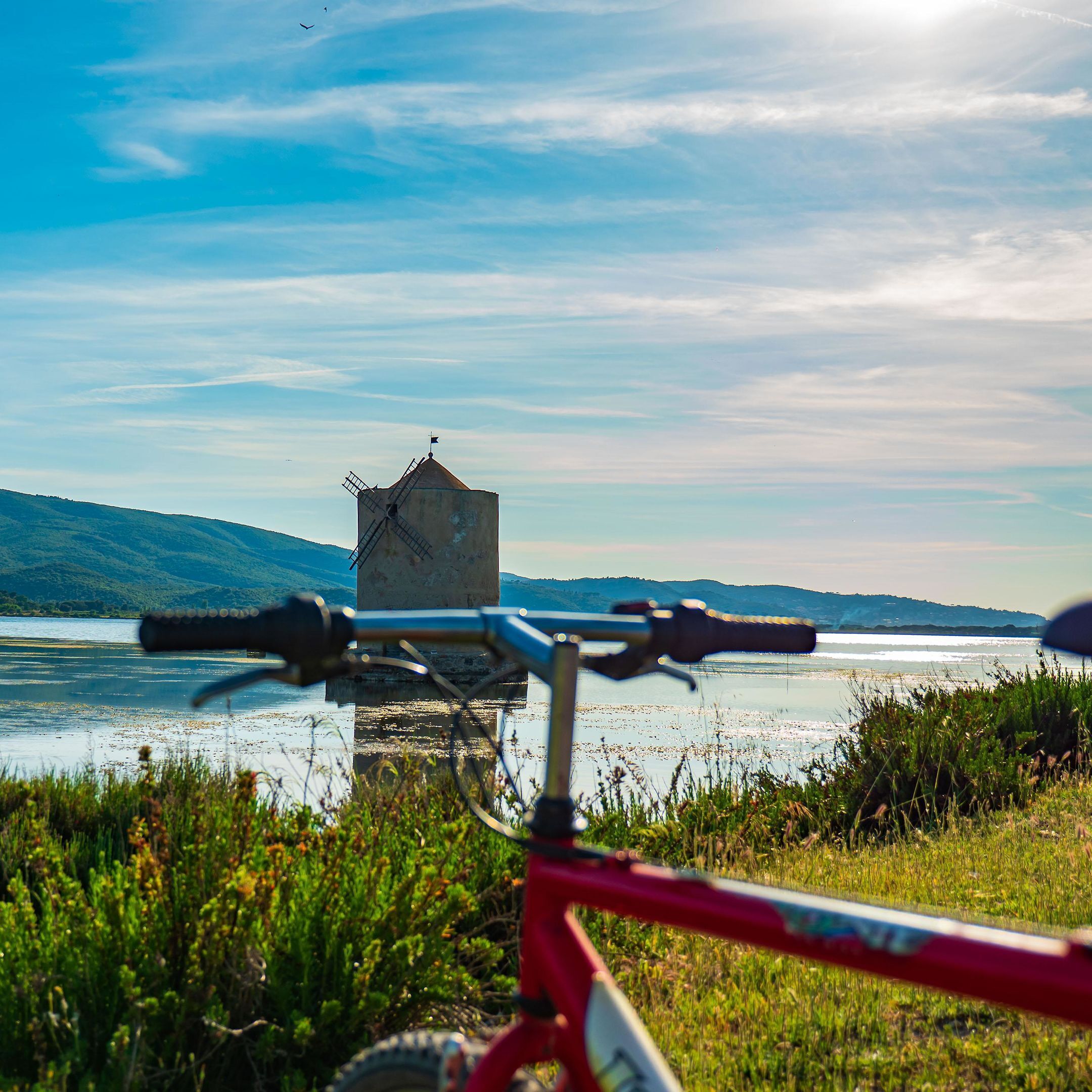A bicycle in the foreground with a view of a water body and distant hills.