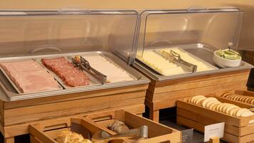 Een buffet met diverse gerechtjes, waaronder vleeswaren, kazen en brood.