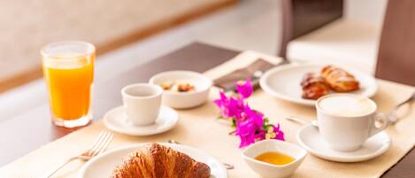 A breakfast setting with croissants, coffee, and orange juice on a table.