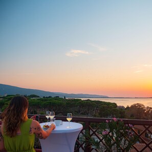 A woman dining at a table with a view of the sunset over a body of water.