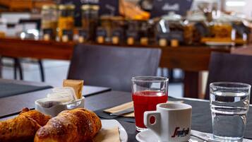 Ein Frühstückstisch mit Croissants, einem roten Getränk und einem Wasserglas.