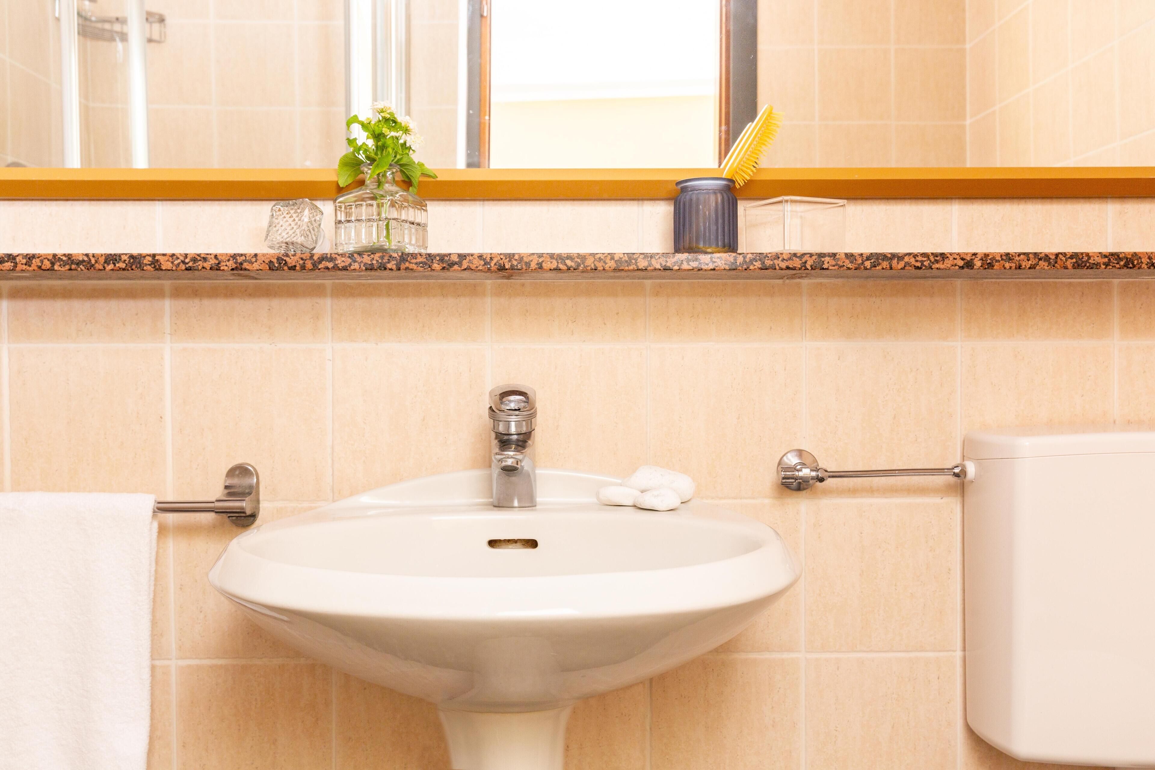 Een badkamer met een wastafel, toilet en een spiegel boven de wastafel.