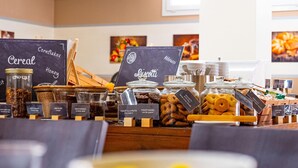A breakfast buffet with various food options including cereal, honey, and biscotti.