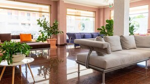 A modern lobby with a sofa, a chair, and potted plants.