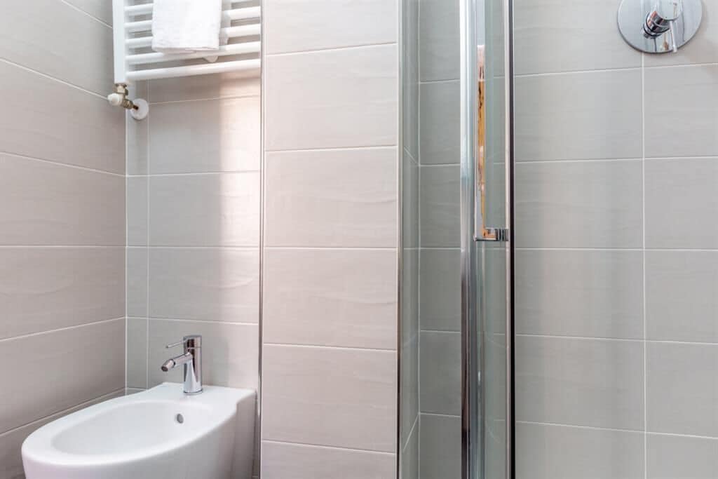 Une salle de bain moderne avec une douche à parois de verre, un lavabo sur colonne et un porte-serviettes.