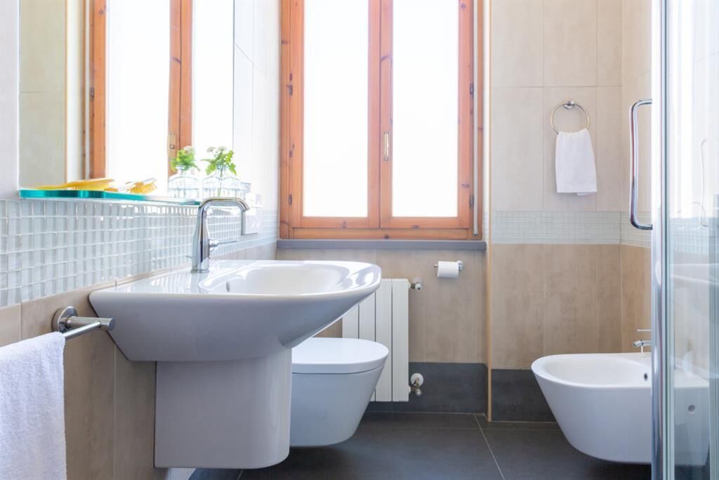 Een moderne badkamer met een wastafel, toilet, bidet en een douchecabine met glazen wanden.