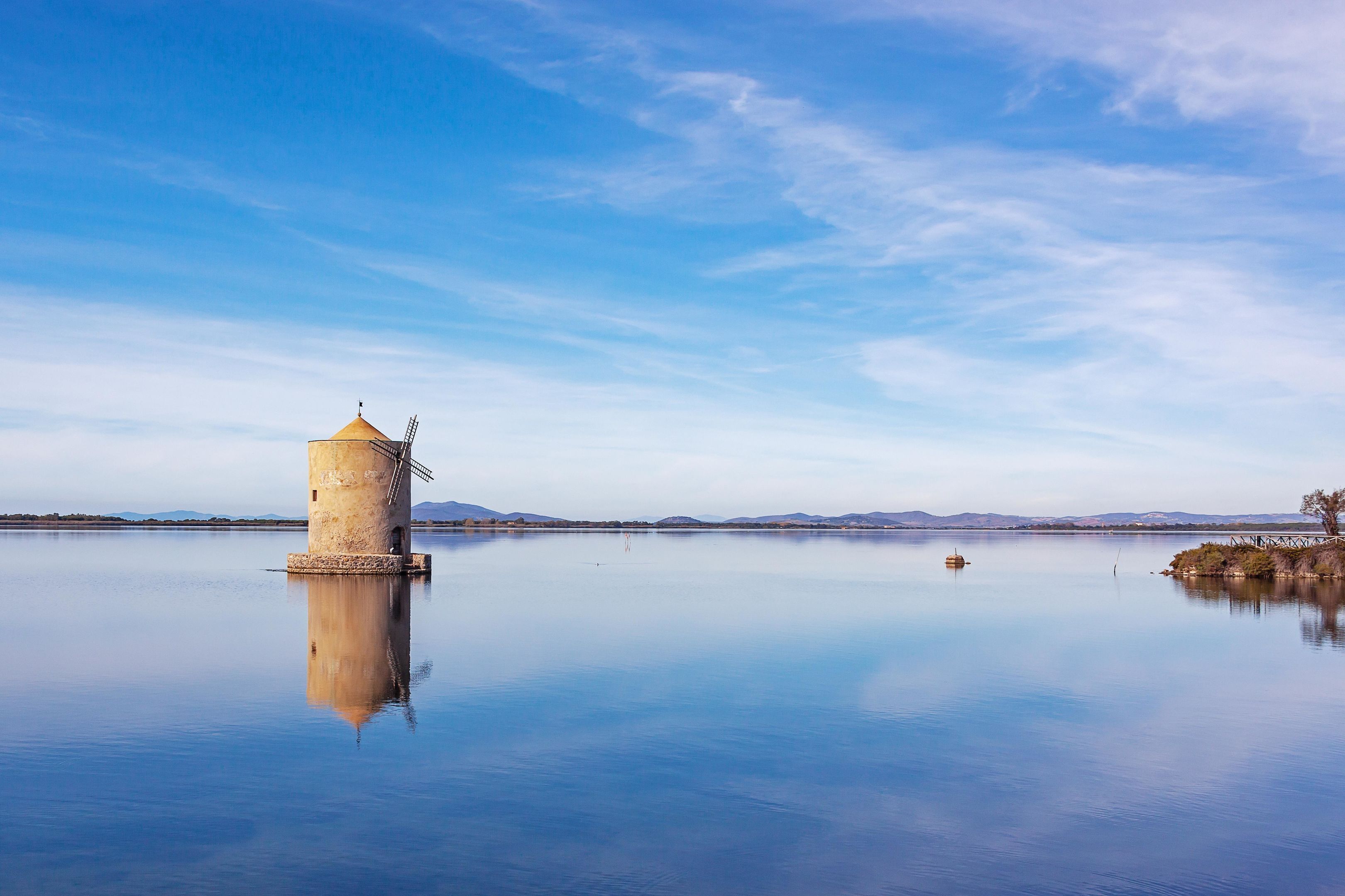 A calm lake with a solitary tower and distant mountains.