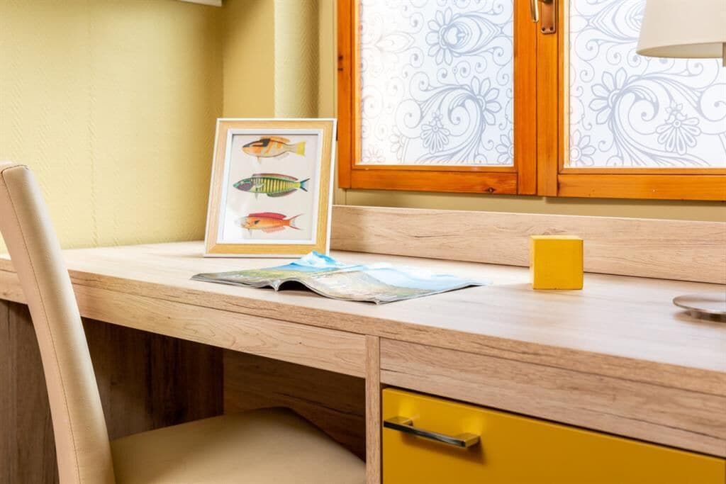 A wooden desk with a framed fish picture, a yellow mug, and a map.