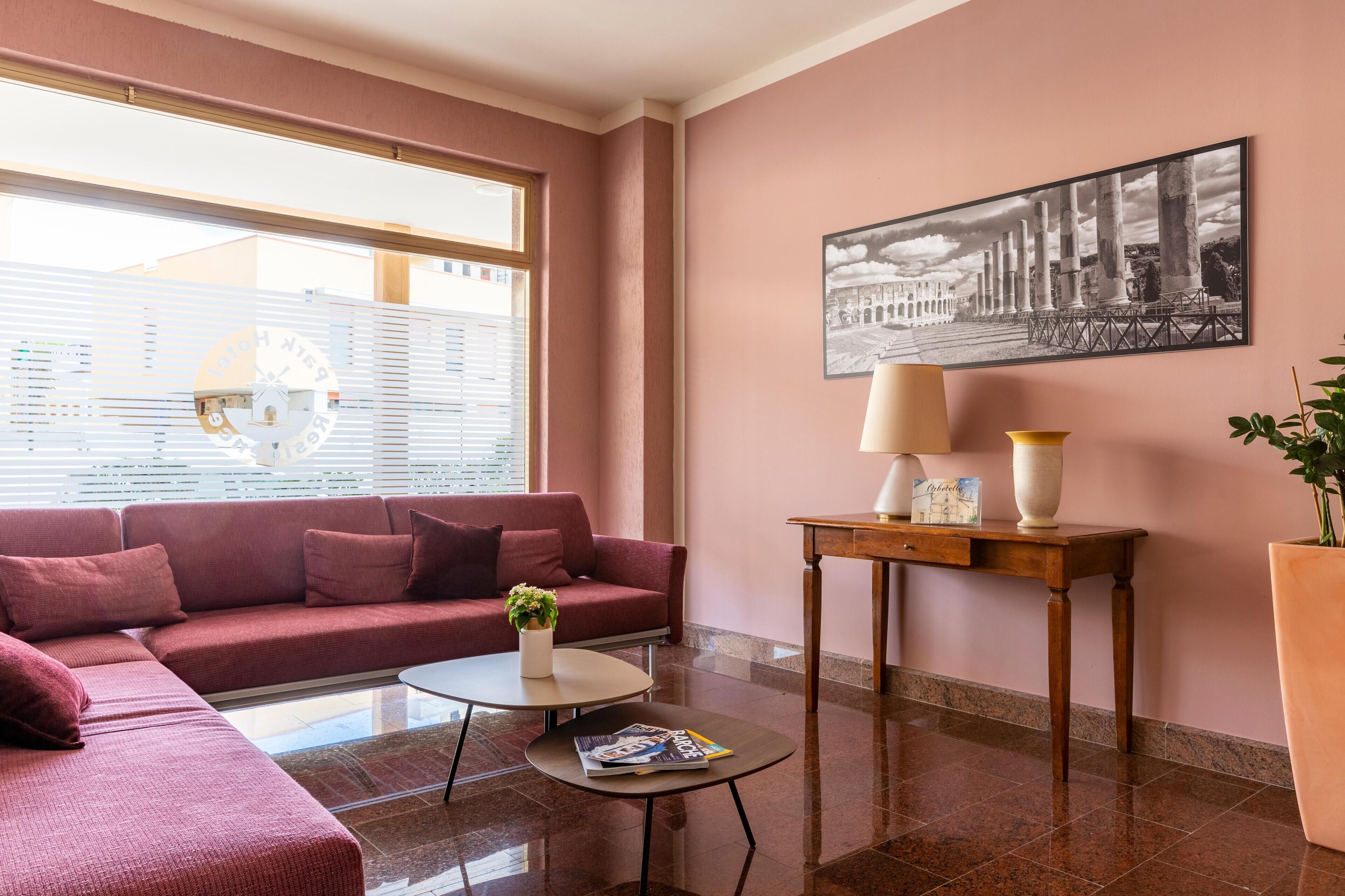 Un salon moderne avec un canapé rouge, une table basse, une lampe et un tableau encadré au mur.