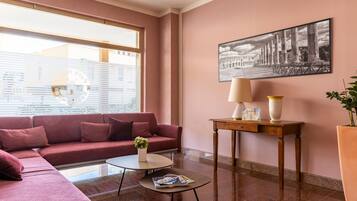 Un salon moderne avec un canapé rouge, une table basse, une lampe et un tableau encadré au mur.