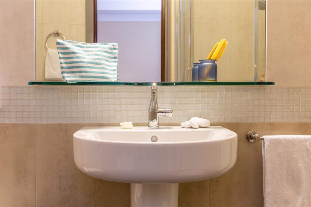 A bathroom with a white sink, a mirror above it, and a towel rack.