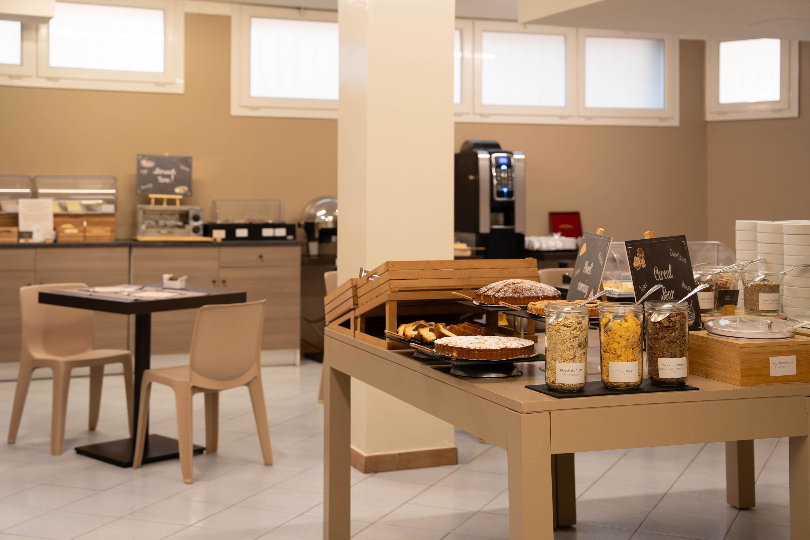 A breakfast buffet with various food items and a coffee machine in a modern kitchen setting.