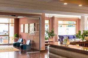 A hotel lobby with seating, a reception desk, and large windows. - Park Hotel Residence (Orbetello)