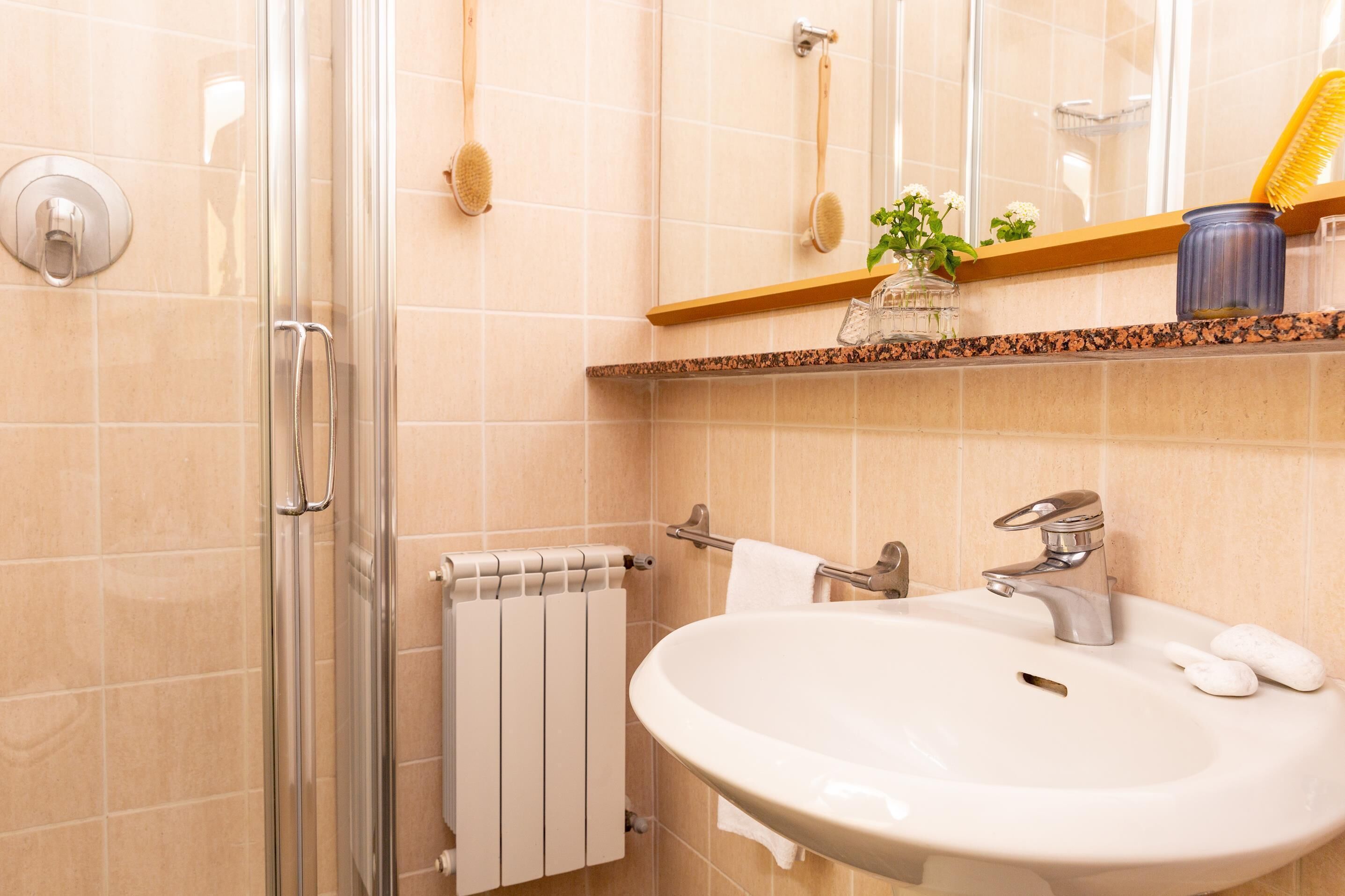 Un baño con cabina de ducha de vidrio, un lavabo blanco con grifo plateado y un espejo sobre el lavabo.