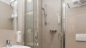 Un baño moderno con ducha envuelta en cristal, lavamanos e inodoro.