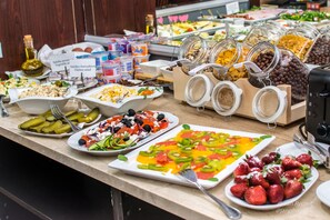 A buffet with various food options including salads, fruits, and dairy products.