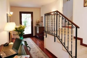 A staircase with a decorative railing, a desk with a laptop and a lamp, and a door leading to another room. - Villa Crispi (Mestre)