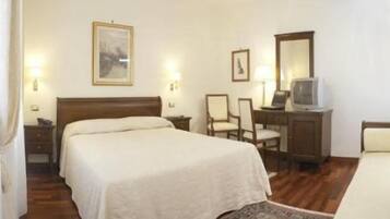 Une chambre d’hôtel comprenant un lit, un bureau avec une chaise, une télévision et un miroir.