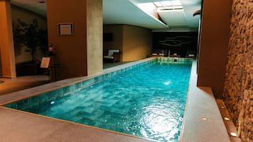 An indoor swimming pool with clear water, surrounded by walls and a ceiling with skylights.