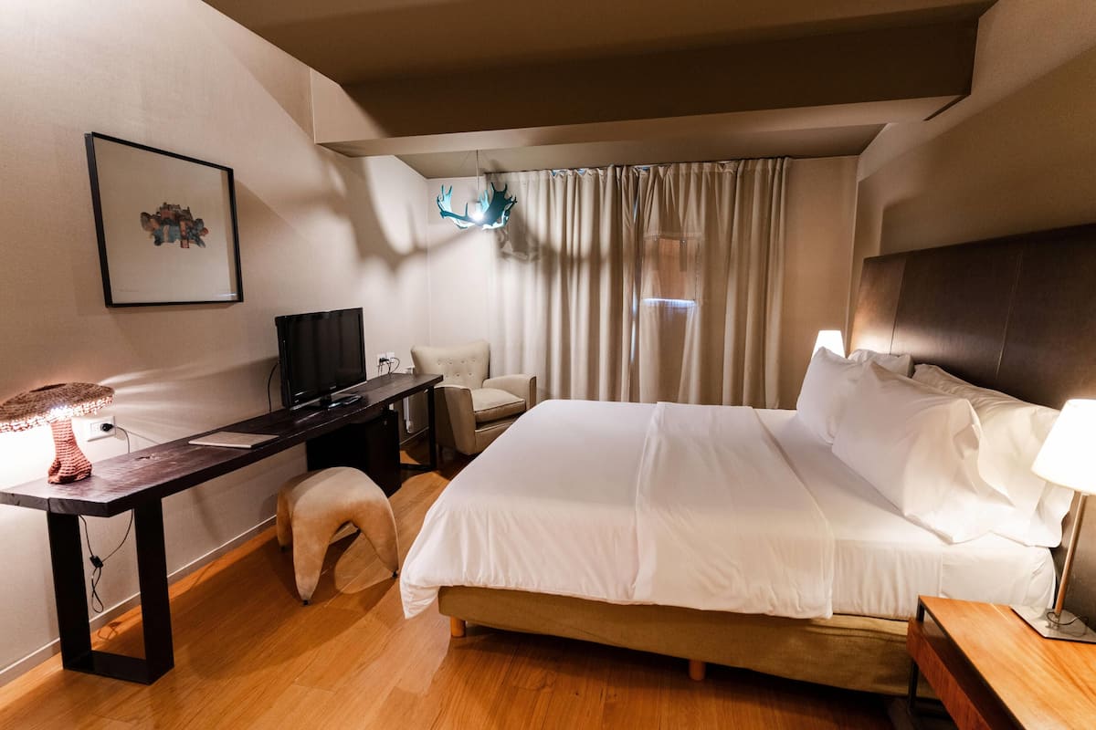 Une chambre d’hôtel équipée d’un lit, d’un bureau, d’une chaise, d’une lampe et d’un téléviseur.