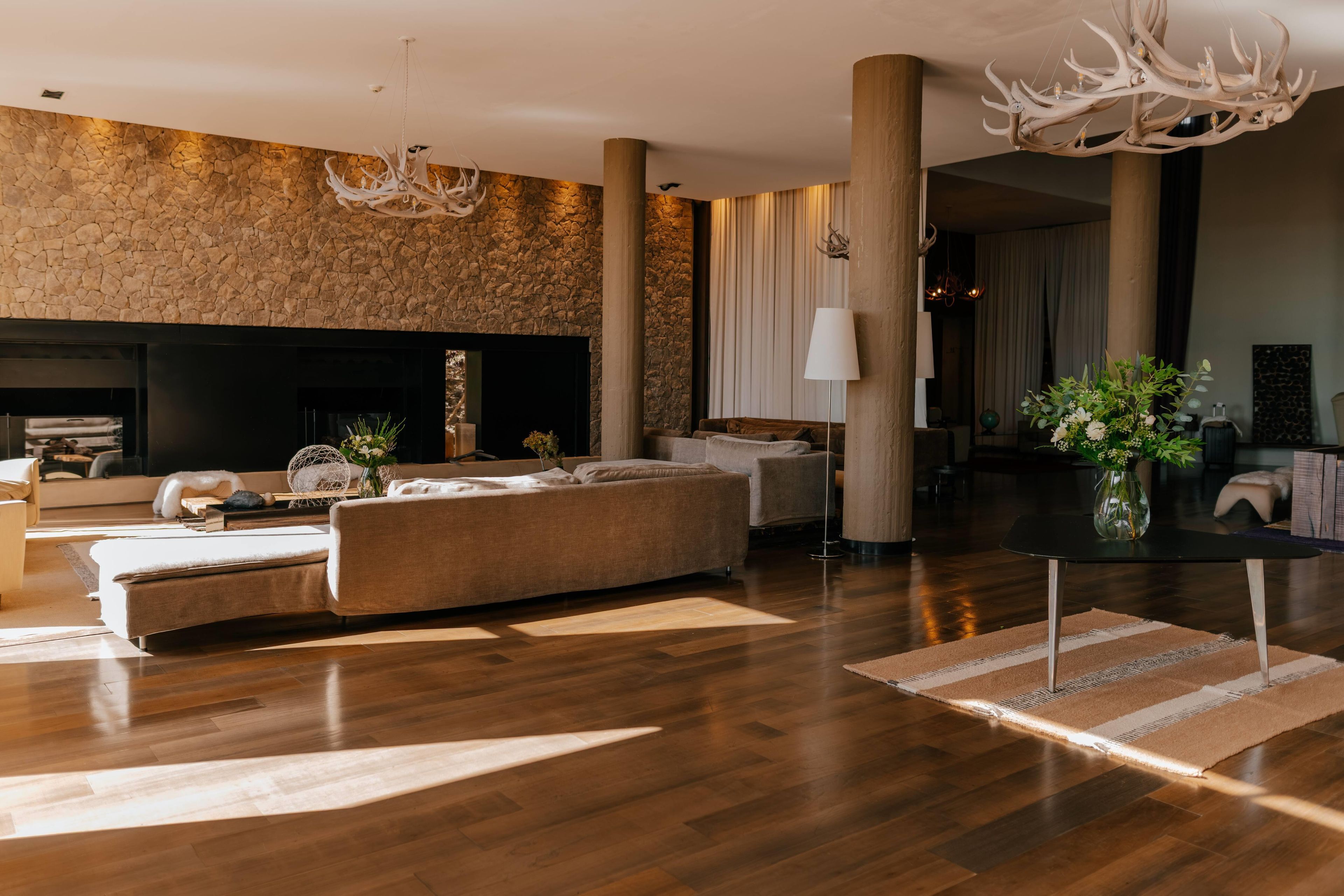 A spacious living room with a fireplace, a large sofa, and a modern chandelier.