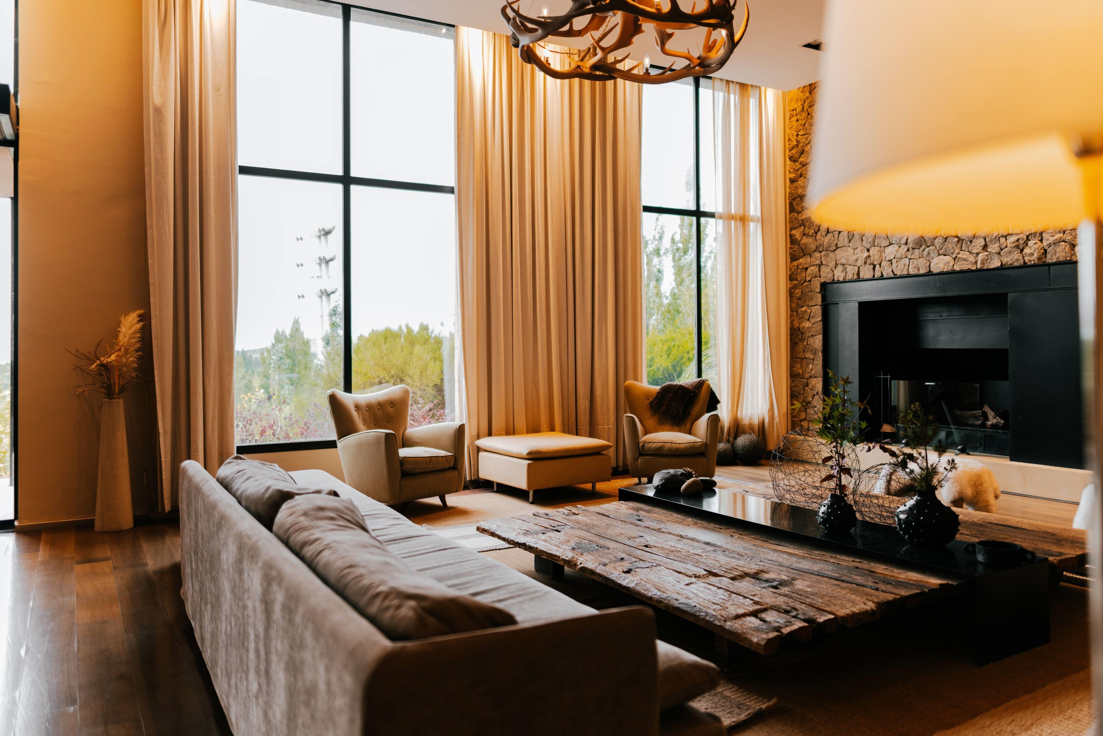 Una sala moderna con un sofá, sillones, una mesa de centro y una chimenea.