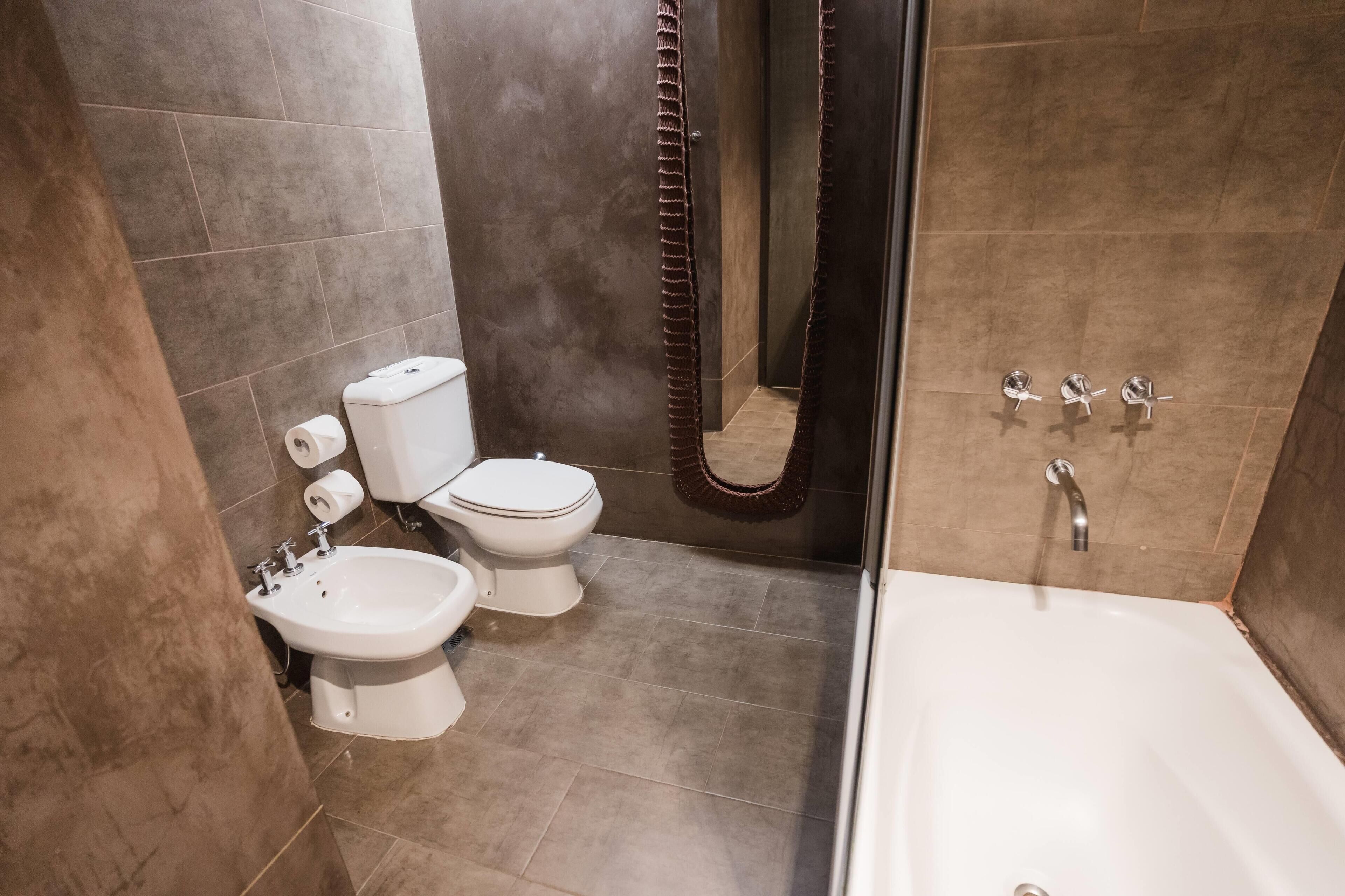 Un baño moderno con bañera, inodoro, bidé y cortina de ducha.