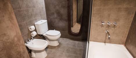 A modern bathroom with a bathtub, toilet, bidet, and a shower curtain.