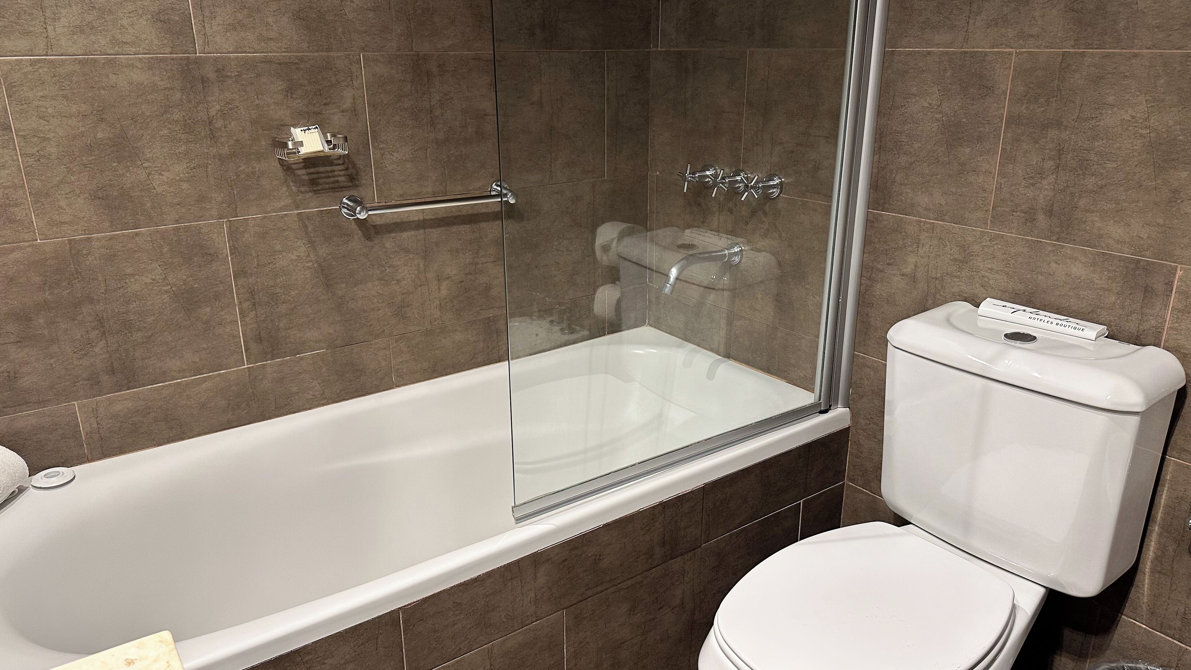 Un baño con ducha envuelta en vidrio, una bañera blanca y un inodoro.