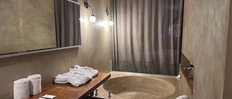 Un baño moderno con un tocador de madera, una bañera grande y un espejo.