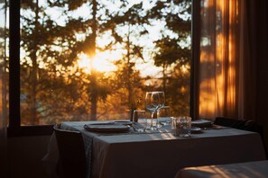 Mesa lista para comer con vista a árboles y luz solar que entra por la ventana.