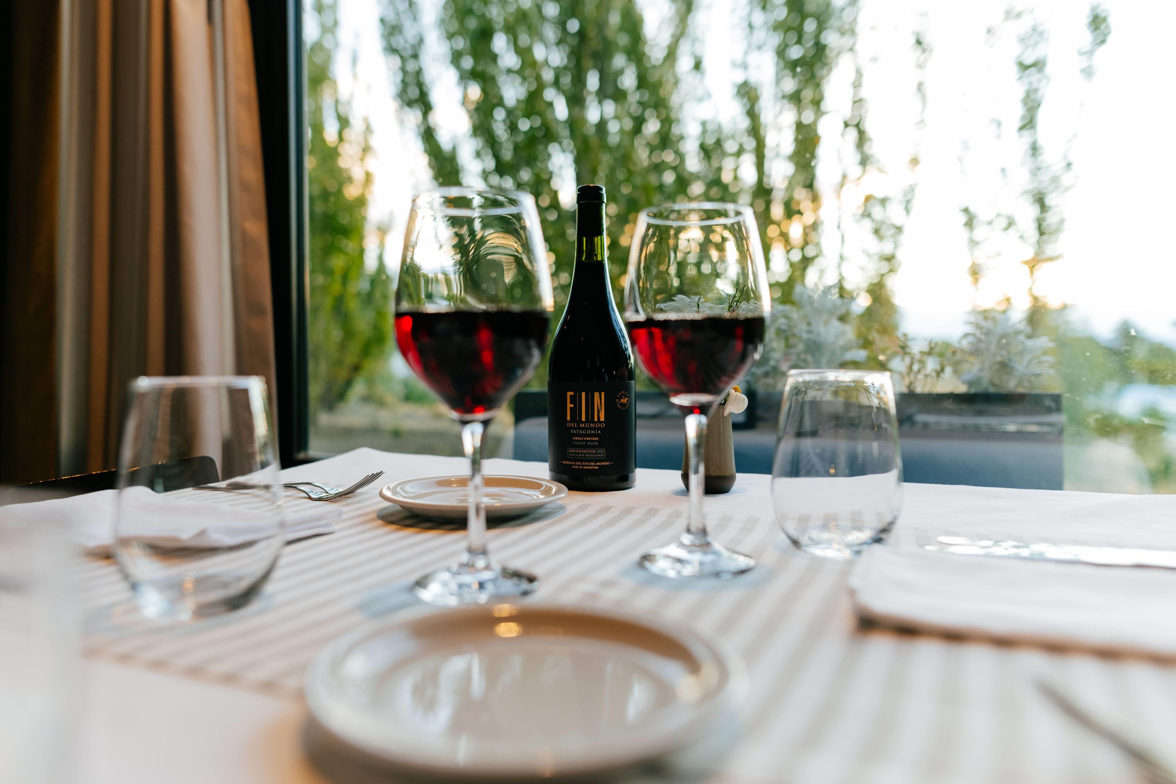 A table set for dining with wine glasses, a bottle, and cutlery.
