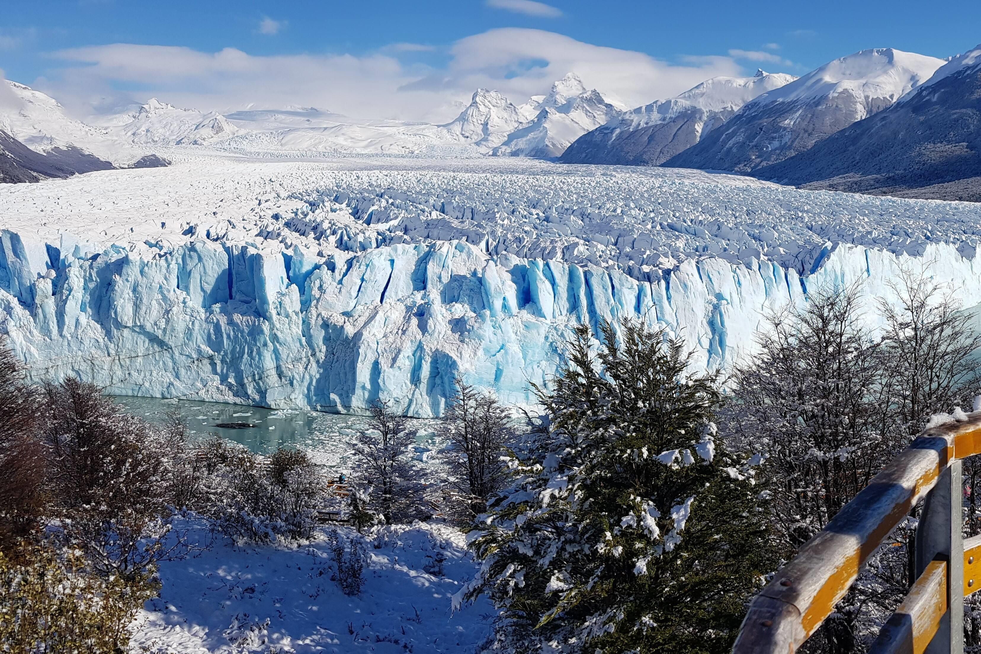 Un glaciar con una vista clara de su hielo azul y el paisaje nevado circundante.