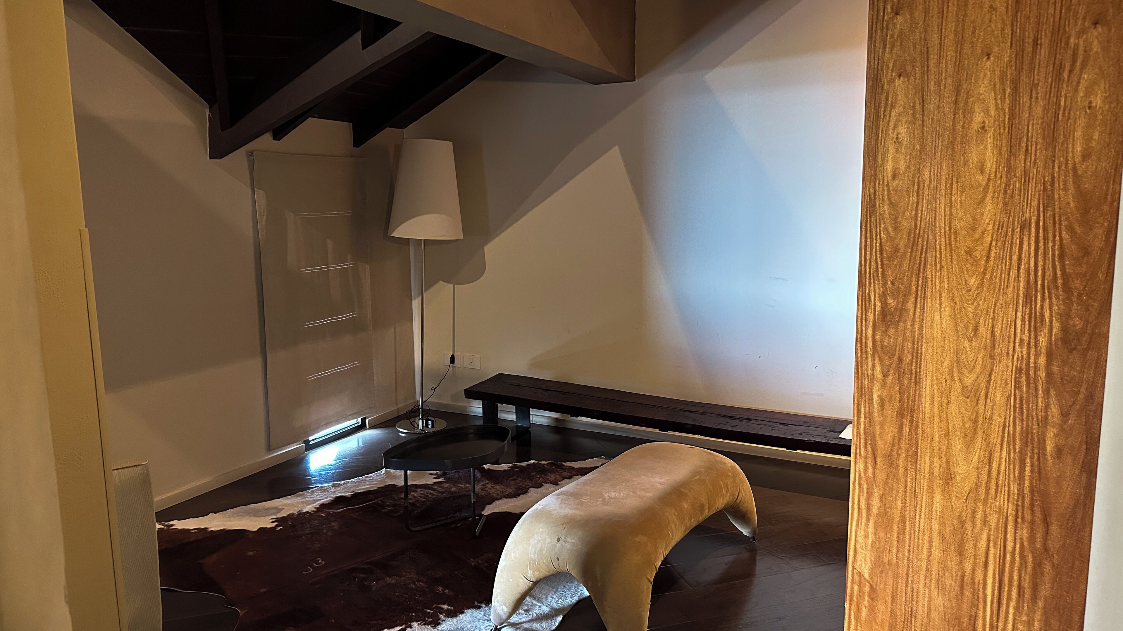 A modern interior with a dark wooden bench, a white sofa, and a floor lamp.