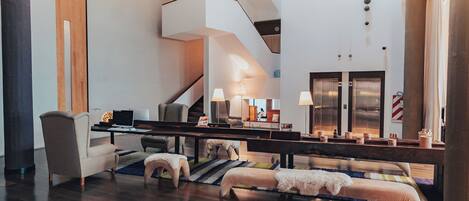 Ein großzügiger Wohnbereich mit hoher Decke, einer Treppe und einer Sitzecke mit Sofa und Hocker.